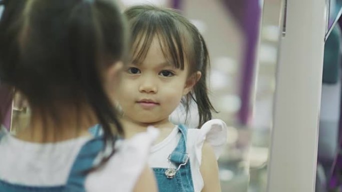 泰国女童用镜子的倒影使自己的脸变得幽默