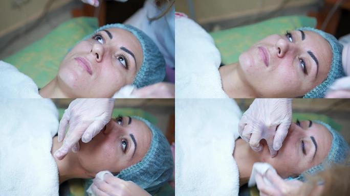 在美容中心为女性客户制作美容面膜的女性美容师。面部清洁