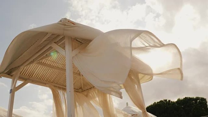 海边度假胜地即将来临的暴风雨。强风在度假村的海滩日光浴床上形成白色的天篷布。4k视频