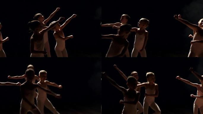 一群芭蕾舞演员在黑暗中的舞台上跳舞