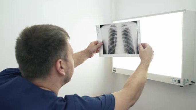 成人医生握住他的手，并讨论x射线照片。一名穿着医生衣服的男子在医院检查医疗设备上的照片