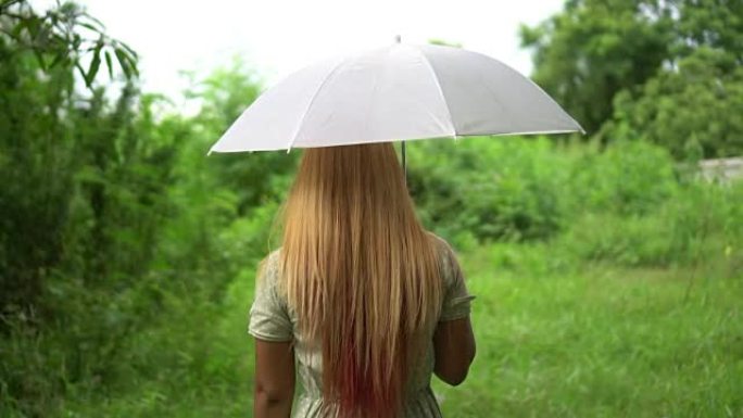 女人在雨下走路手拿着白伞