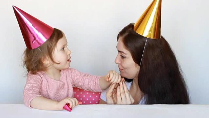 妈妈和孩子在生日聚会上开心，在游戏中玩耍。母亲，她的女儿在白色背景上微笑和大笑。3年。家庭和假期