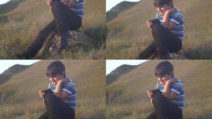 一个男孩坐在大自然的一块岩石上使用手机