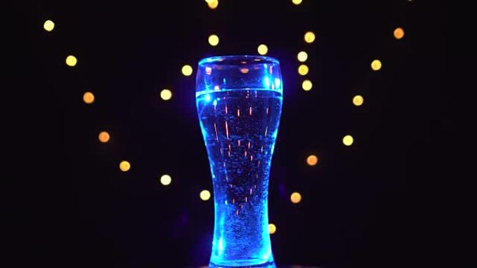蓝光中的一杯水正在旋转。蓝色鸡尾酒。酒吧概念