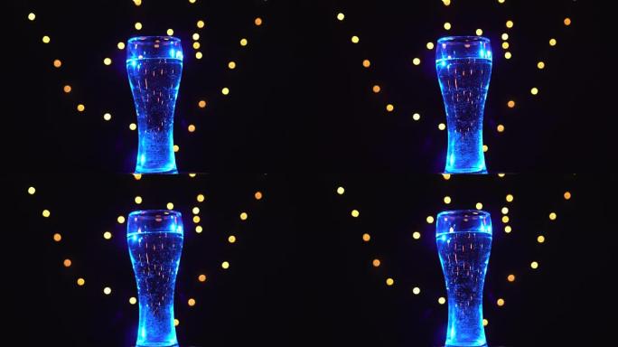 蓝光中的一杯水正在旋转。蓝色鸡尾酒。酒吧概念