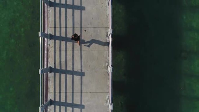 空中: 女孩正在海边的桥上奔跑。