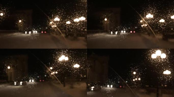 司机在城市的雨夜开车，从里面看。镜头。雨中汽车挡风玻璃上的景色
