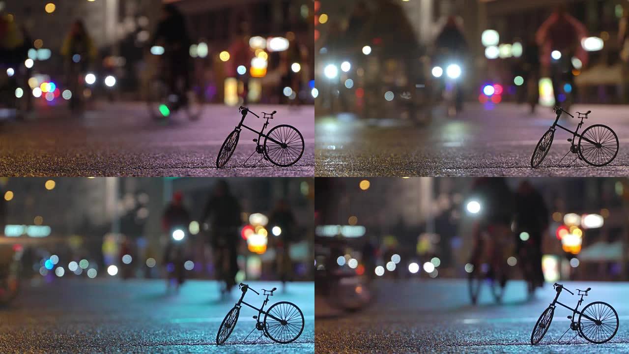 在小规模自行车模型的背景下，许多骑自行车的人在夜间骑自行车游行中被照明的夜间城市街道模糊地骑行。骑自