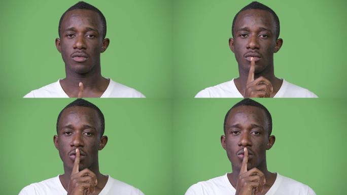 年轻的非洲男子，手指在绿色背景下的嘴唇上