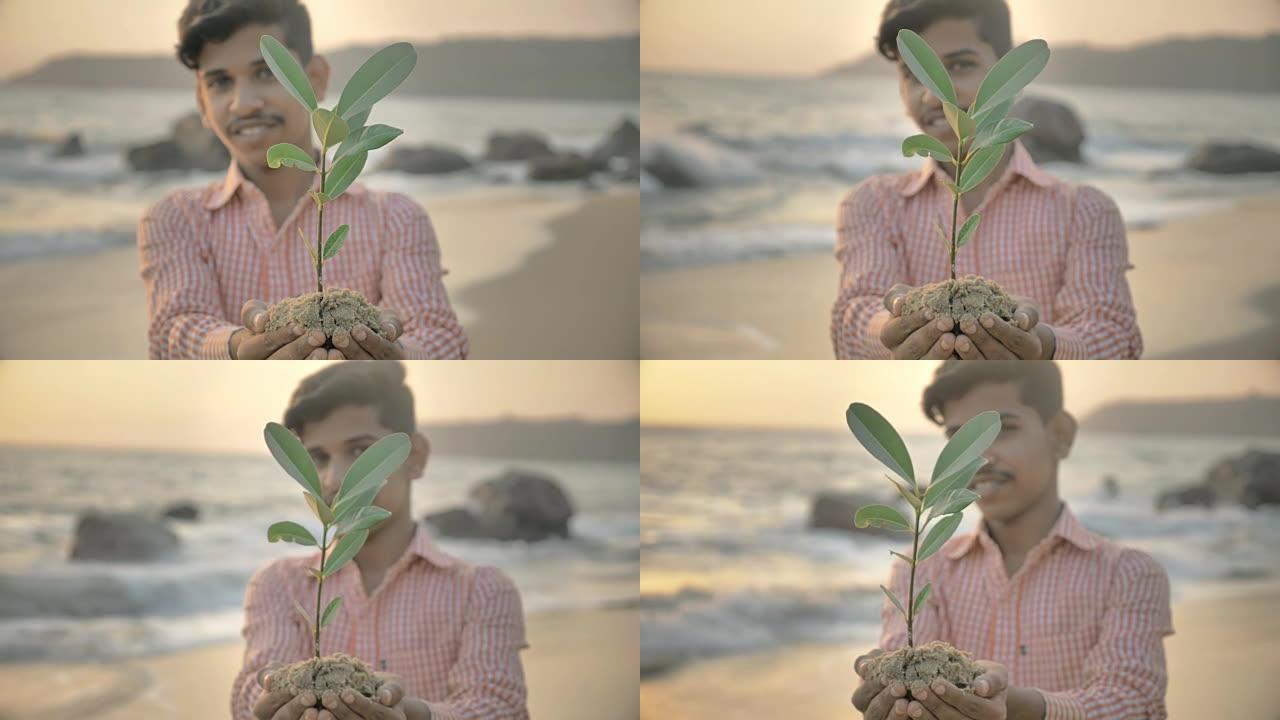 印度小男孩或少年手持一株绿色小植物