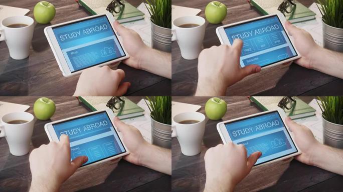 在办公桌上使用数字平板电脑查看出国留学网页