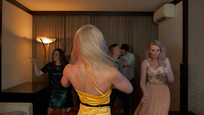 女人在派对上跳舞。朋友生日时穿着黄色裙子跳舞的漂亮开朗的金发女孩