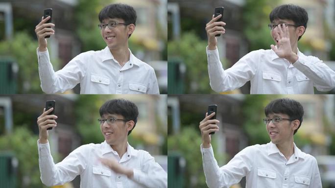 年轻快乐的亚洲商人视频在户外街头打电话