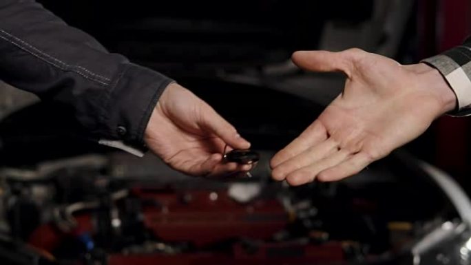 机械师和顾客在汽车修理厂握手的特写镜头。
