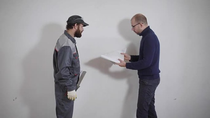 客户和修理工站在白色墙壁背景上的公寓中，业主正在解释该怎么做