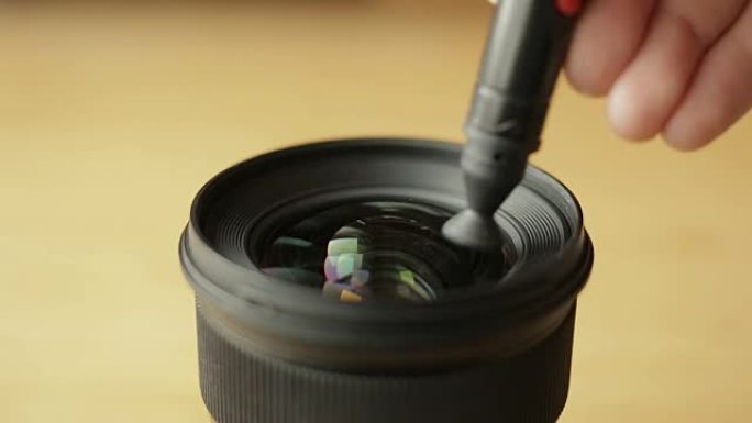 刚开始的摄影师或视频摄影师正在用专业的光学清洁笔仔细清洁镜头的前玻璃