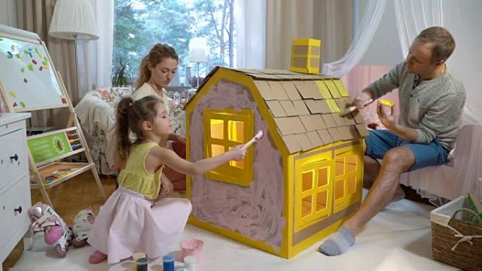 Young family with child building and painting toy 