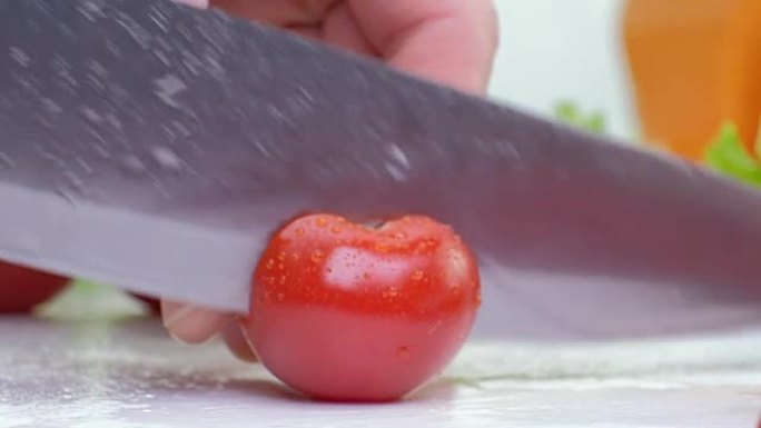 用菜刀在白板上切割红色樱桃番茄，白色背景，特写镜头全高清