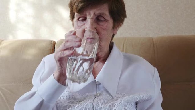 不健康的老妇人吃药，喝水。