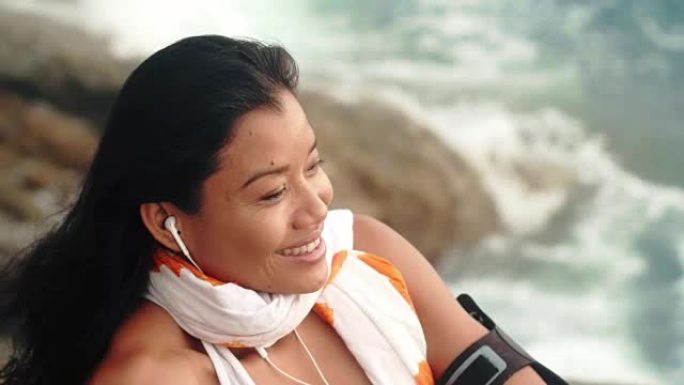 微笑的女人在海边听音乐放松和冥想