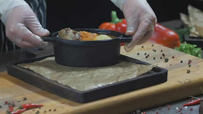 厨师正在铁锅里供应带肉的汤。木板
