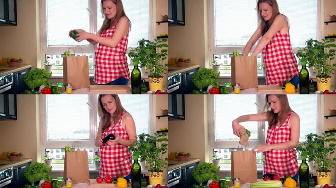 微笑的怀孕妻子在厨房里卸下装有有机蔬菜的购物袋