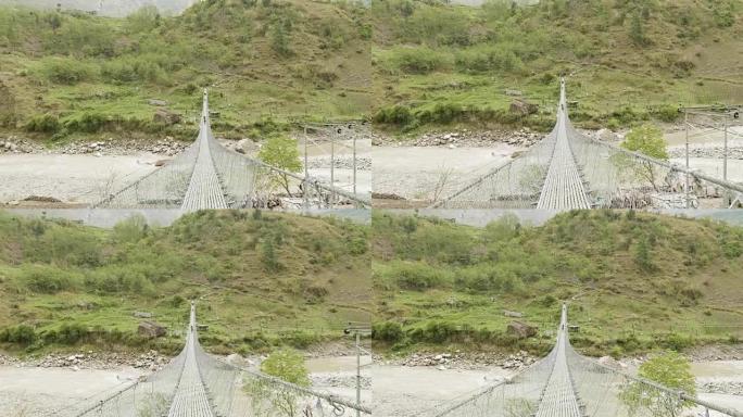 背包客在尼泊尔河上的吊桥上行走。马纳斯鲁巡回赛。