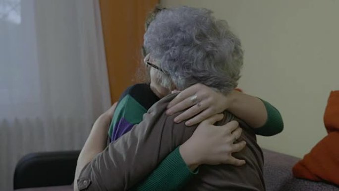 年轻的女学生在家探望她后，拥抱和亲吻她的祖母老师再见