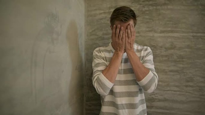 年轻悲伤的斯堪的纳维亚男子在家里遮住脸时哭泣