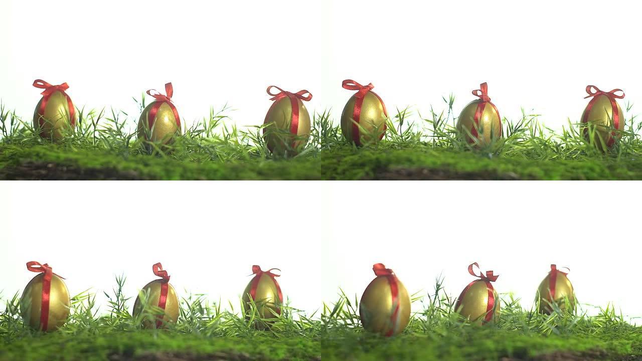 绿色草地上用红丝带绑着金色油漆的鸡蛋