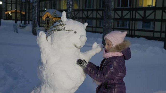 小女孩堆雪人，在雪地公园里看着它