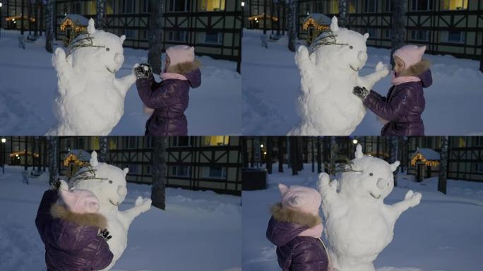 小女孩堆雪人，在雪地公园里看着它