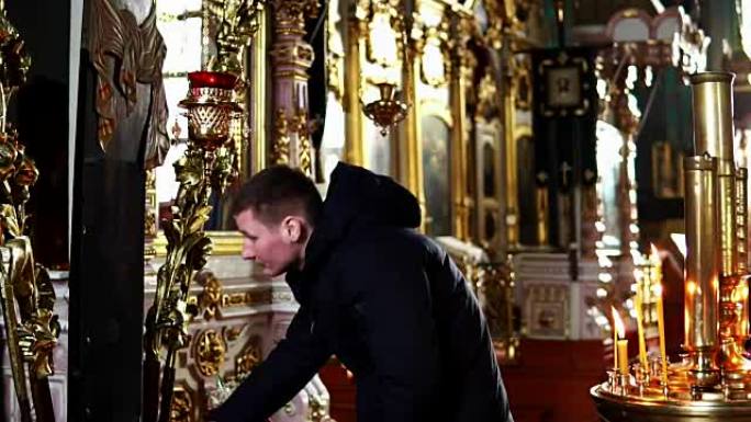 年轻人在东正教教堂鞠躬亲吻十字架