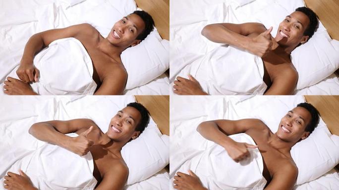 躺在床上的快乐非洲男子竖起大拇指，俯视图