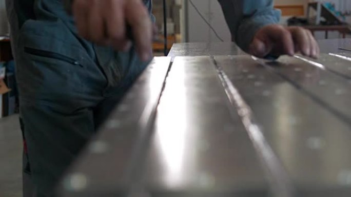 工人用刮刀清除金属零件上的毛刺，用于数控机械生产