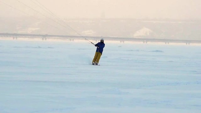 慢动作:一名男运动员正在滑雪板上放风筝。他在一个大湖的冰面上打滚。翻滚时，他会进行各种跳跃、动作和其