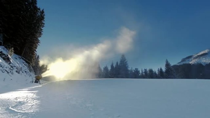 黄色的雪炮在冬天顶着太阳站在雪山上，并在美丽的山脉，白雪覆盖的松树和滑雪场的背景下产生一列雪