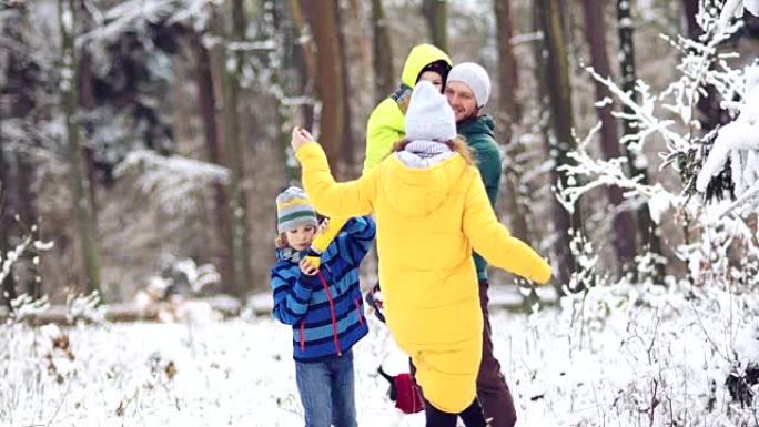 冬季森林中的全家福。幸福的家庭和宠物在白雪覆盖的树木的背景下