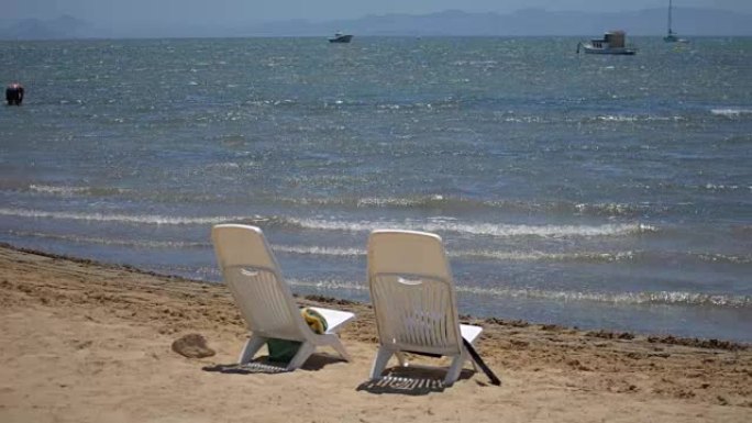 海滩上的两把空塑料椅子