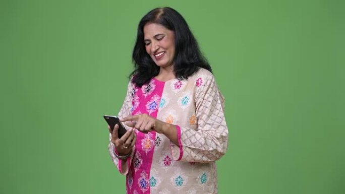 成熟快乐美丽的印度女人在使用电话时微笑
