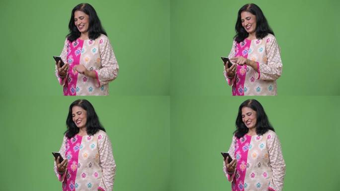 成熟快乐美丽的印度女人在使用电话时微笑
