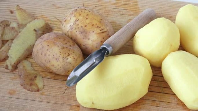 Potato peeler and peelings of tuber, lying on wood