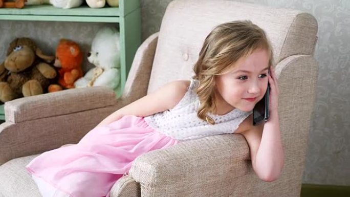 小女孩坐在椅子上，用手机说话。快乐，微笑，特写