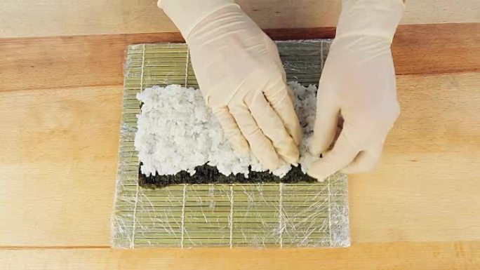 厨师通过将米饭放在藻类Nuri上准备寿司