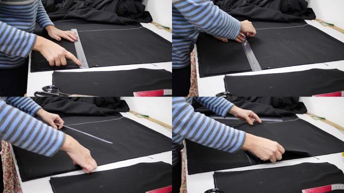 带粉笔和尺子的裁缝师在工作室里测量桌子上的布料