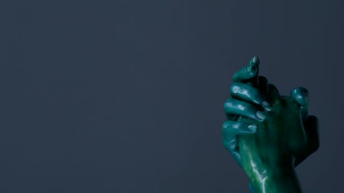 时装模特的双手涂成绿色，用手势和射击显示枪支。时尚视频。