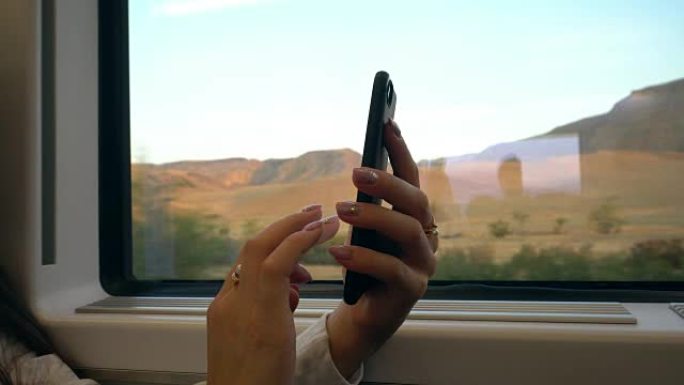 一位年轻女士的手在火车上使用智能手机