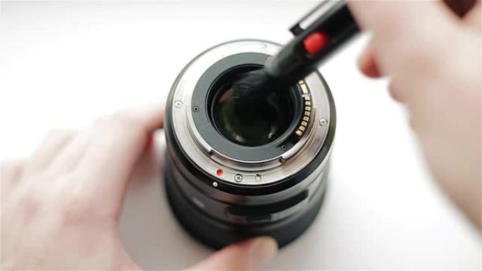 摄影师的手用专业铅笔清洁现代镜头的背面，以保护光学系统