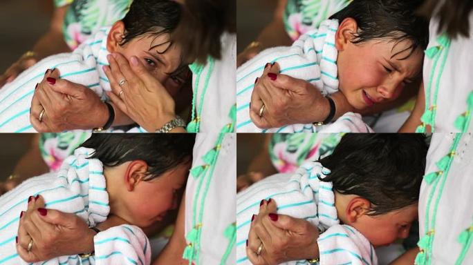 哭泣的孩子被祖母的手臂安慰。小男孩在奶奶的爱中哭泣和哭泣。孩子哭了